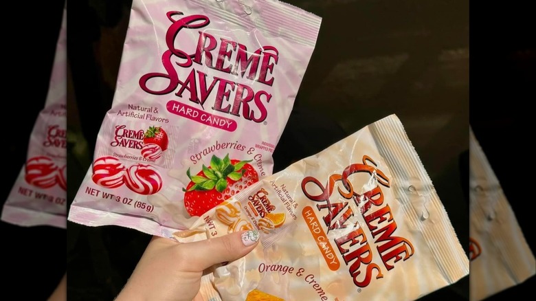 A person holding packs of Creme Savers candy