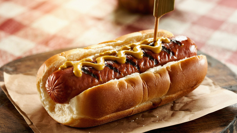Wrinkled hot dog with mustard in a bun
