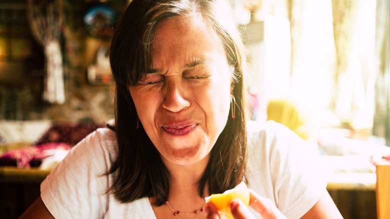 A woman's face puckering from eating something sour.