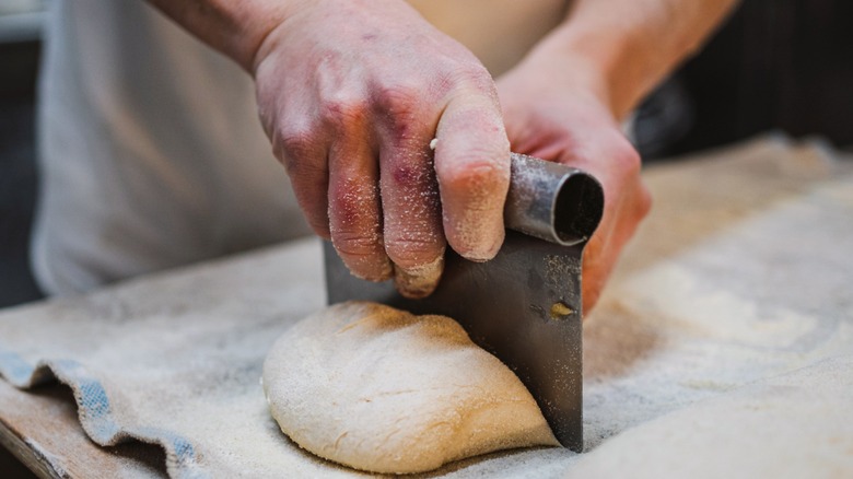 Close up of man's hands holding metal pastry cutter with dough