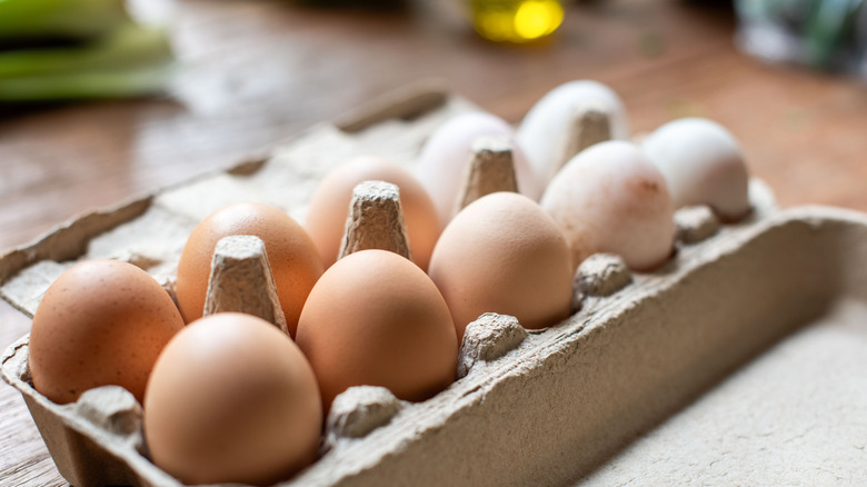 A carton of brown and white eggs sitting on the counter.