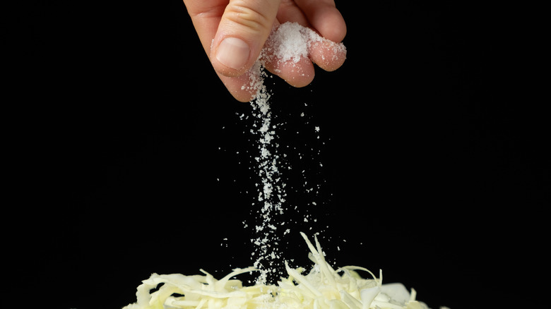 A hand sprinkling salt