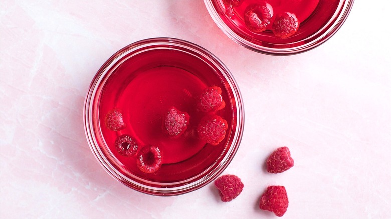 Small clear bowls with red gelatin and fresh raspberries