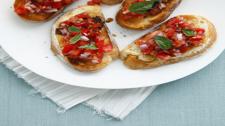 plate of bruschetta topped with tomatoes, onions, and herbs