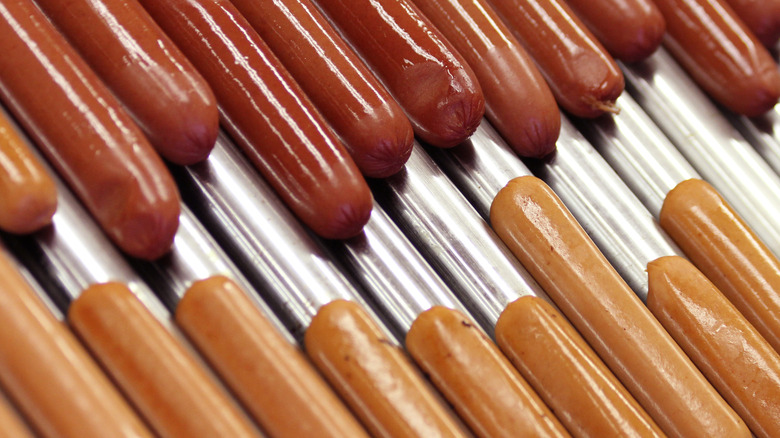 rows of shiny hot dogs on a roller grill