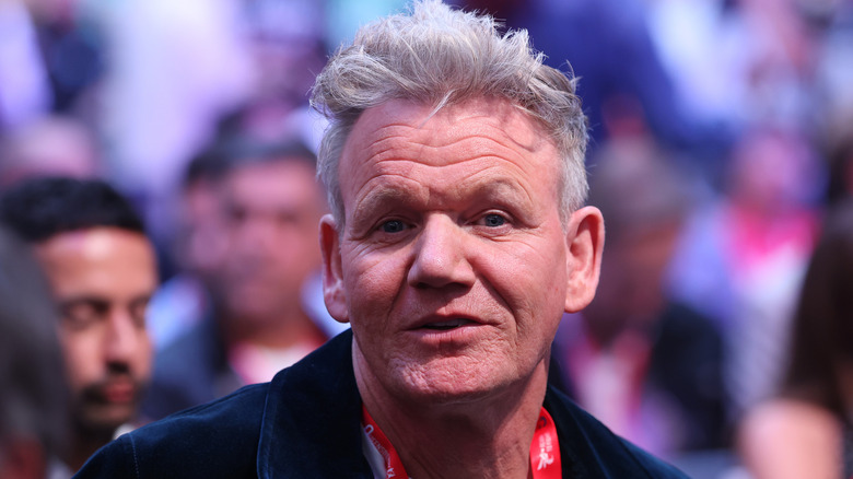 A close-up of Gordon Ramsay's face with a blurred crowd in the background.