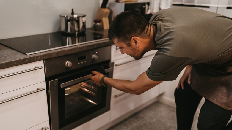 A man checking food in the oven.