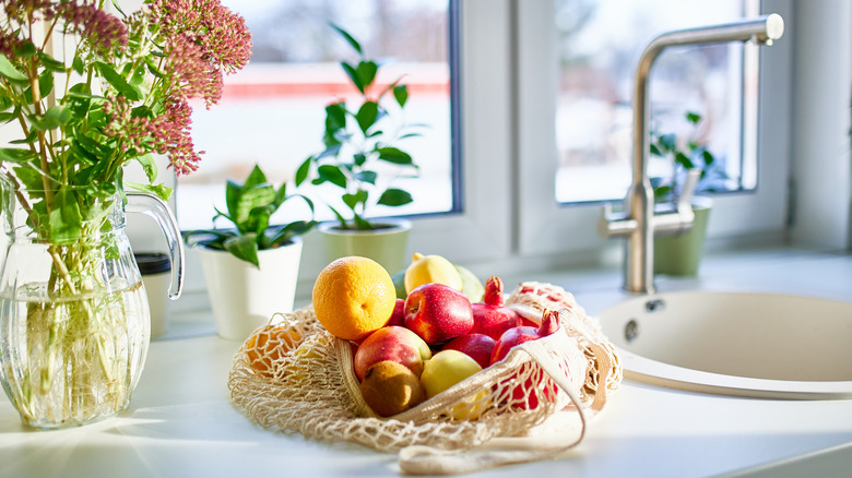A bright bag of fruit on a bright, lovelty kitchen counter.