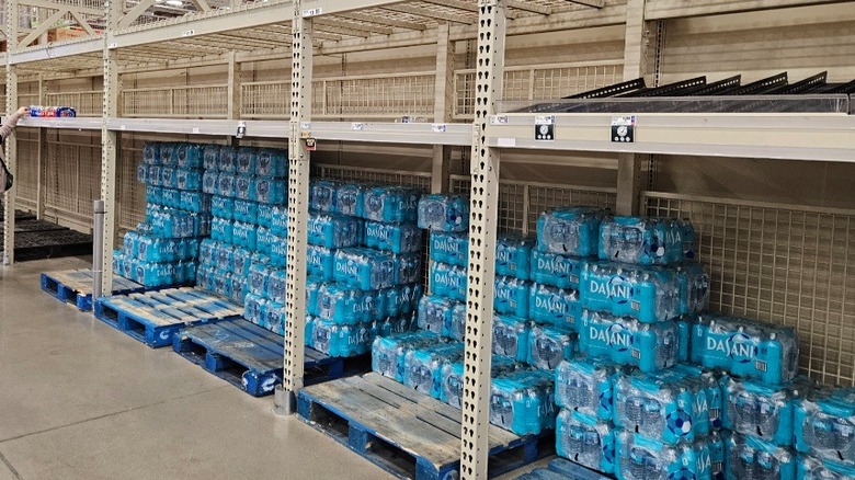 A huge stack of Dasani bottled water surrounded by otherwise empty shelves