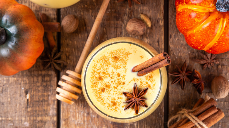 Top-down view of eggnog on a wooden board garnished with cinnamon sticks and anise star