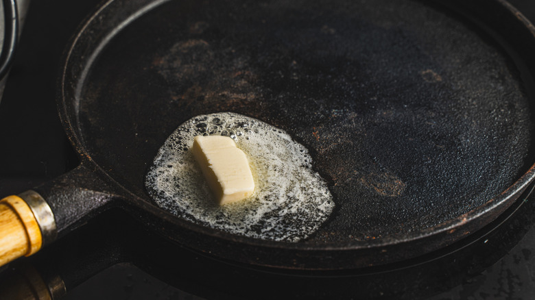 A pat of butter melting in a cast iron pan.