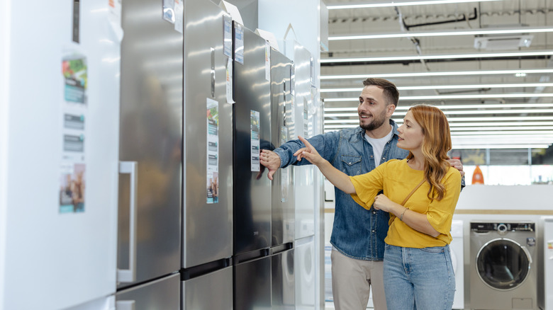 A couple shopping for refrigerators at an appliance store.