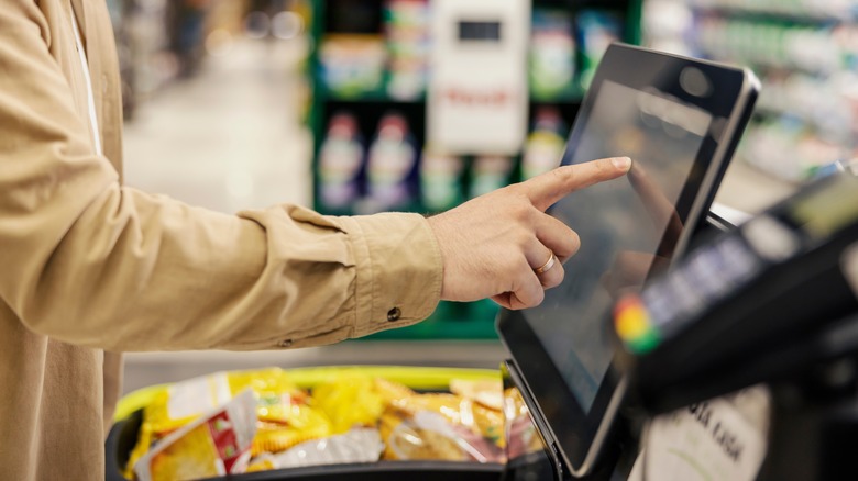 Person using self-checkout with a basket of groceries