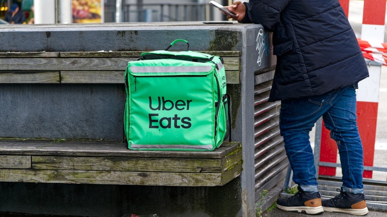 an uber eats delivery bag left on a streetside bench