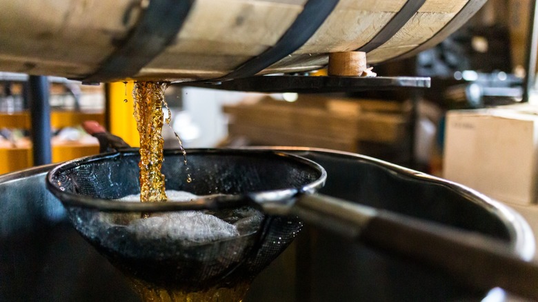 A barrel of bourbon being filtered through a sieve