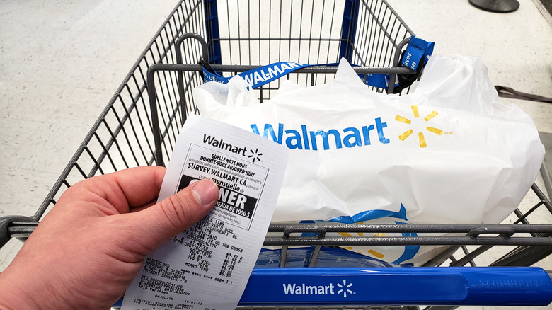 Person holding a Walmart receipt while pushing a cart