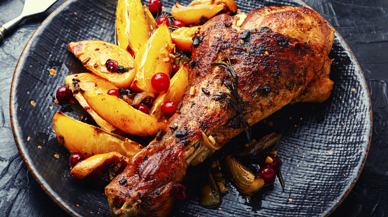 Roasted turkey leg on a plate with sliced fruits