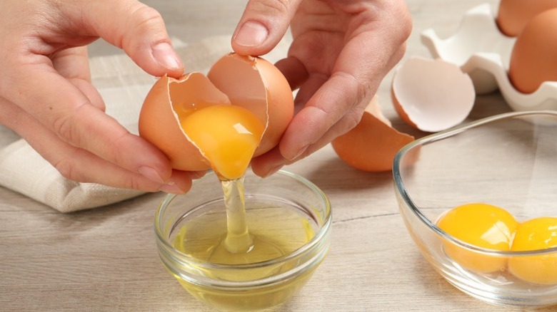 Hands cracking an egg into a bowl