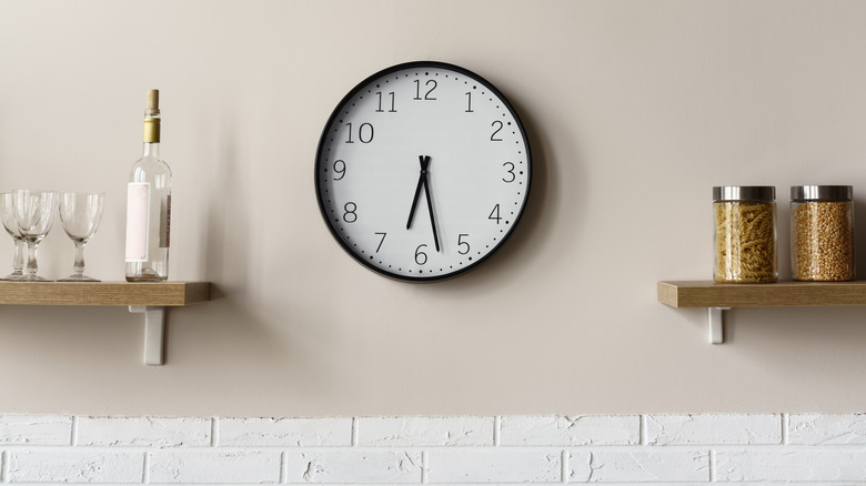 kitchen clock hung between two floating shelves