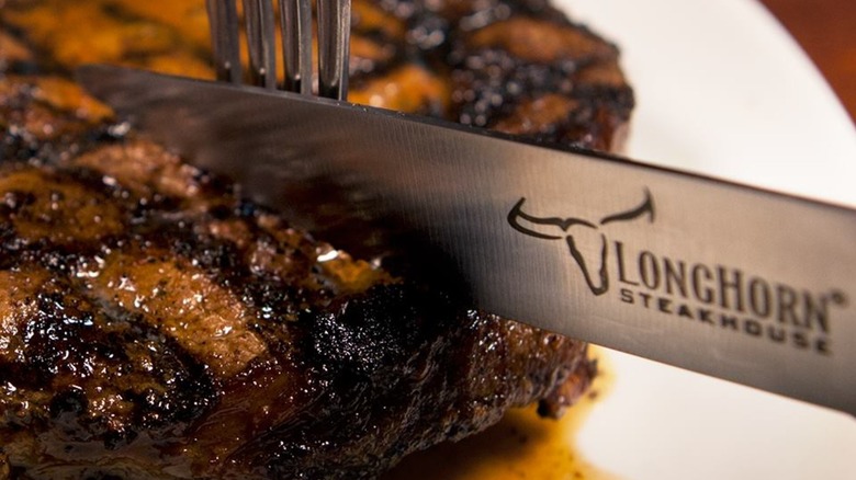 LongHorn Steakhouse-branded knife cutting into a steak