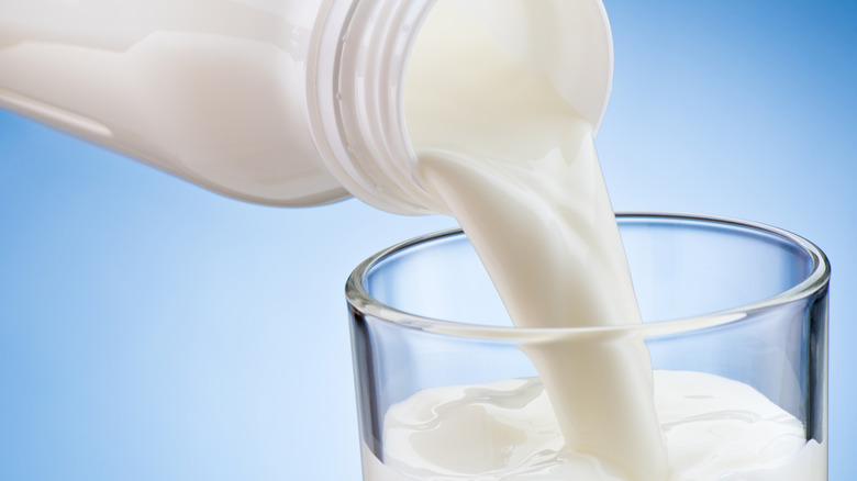 Milk being poured into a glass set against a blue background