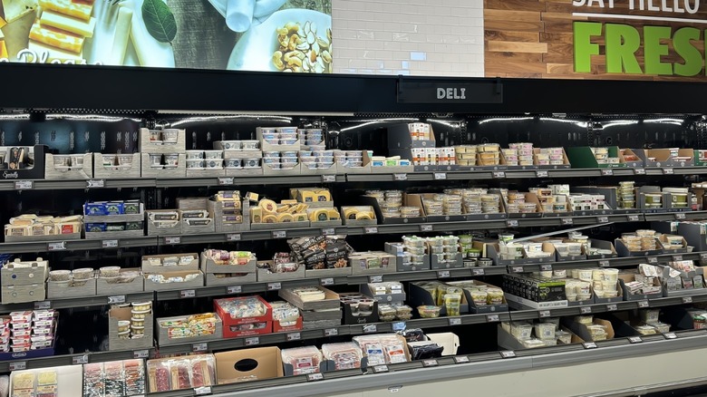 Refrigerated shelves full of packaged cheese and meats in the deli section at Aldi.