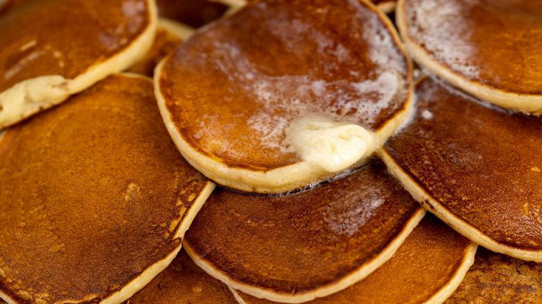 A couple of golden brown pancakes with melted butter