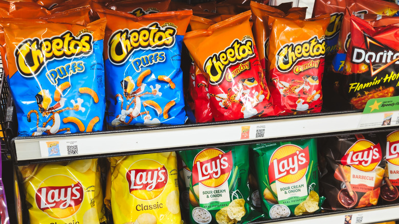 Cheetos, Doritos, and Lay's chips on a grocery store shelf