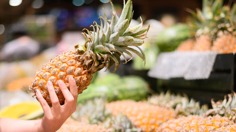 Hand selecting a pineapple at market