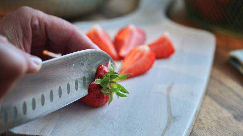 A knife slicing strawberries on a cutting board
