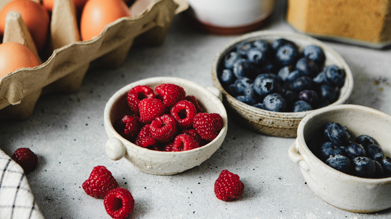 Bowls of raspberries and blueberries on a countertop