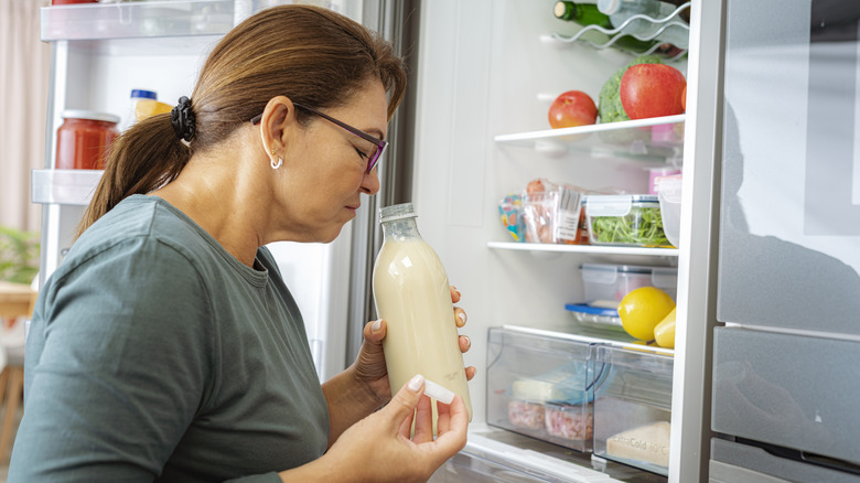 Woman smelling milk from fridge