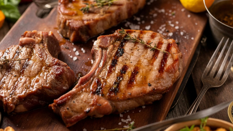 Three grilled pork shops on a cutting board