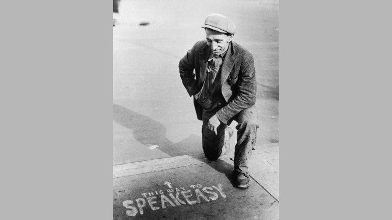 A man looks at a sign pointing the way to a speakeasy