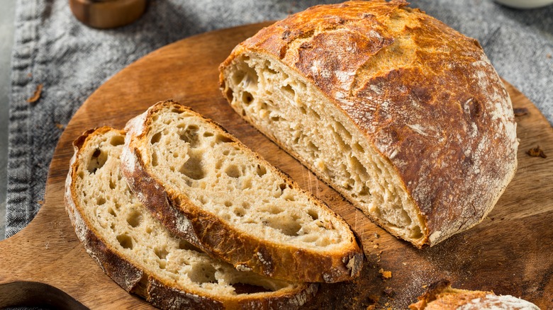 Freshly sliced no-knead bread sits atop a wooden cutting board