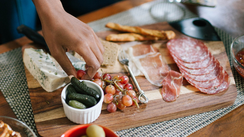 Hand reaching to take a grape from a charcuterie board