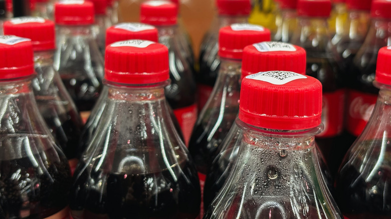 Close-up of the tops of plastic soda bottles, lined up in several rows