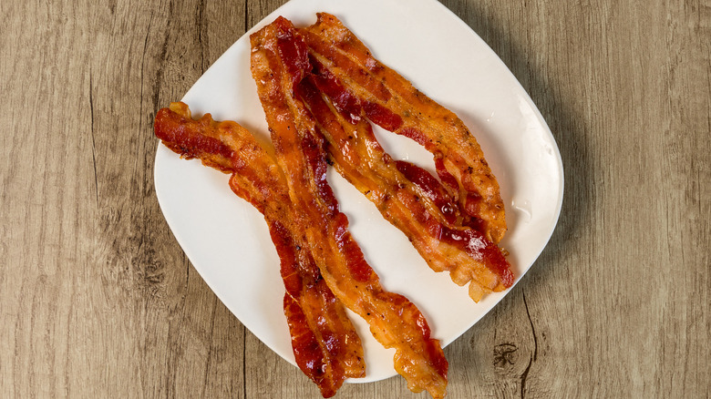 Several rashers of crispy bacon on a plate.