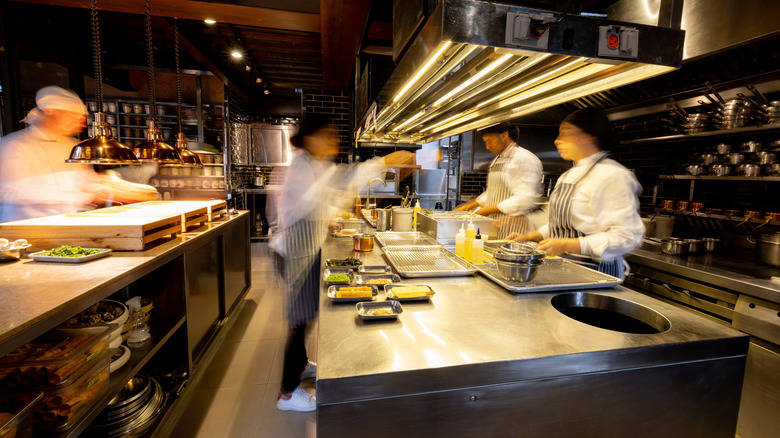 Hectic cooks work in a busy commercial kitchen at a restaurant