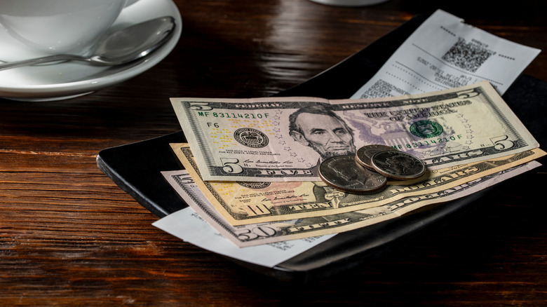 American money sits in a tip tray at a restaurant