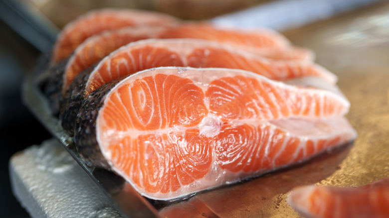 Raw salmon slices on a wooden board.