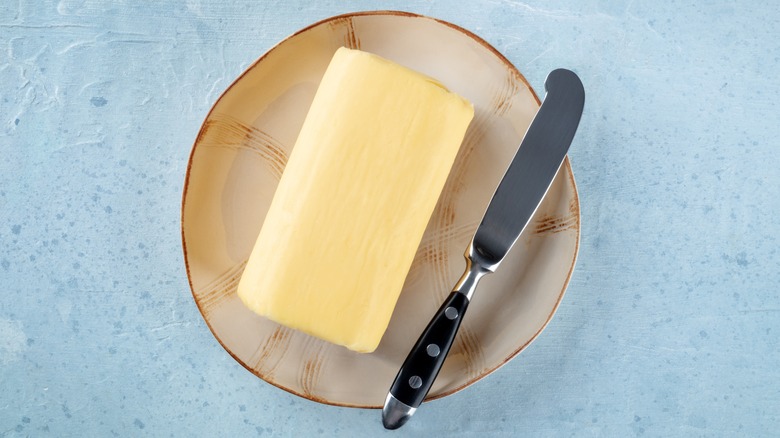 Butter stick on a plate with knife