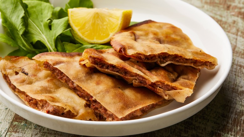 arayes  in a plate with leafy greens and lemon