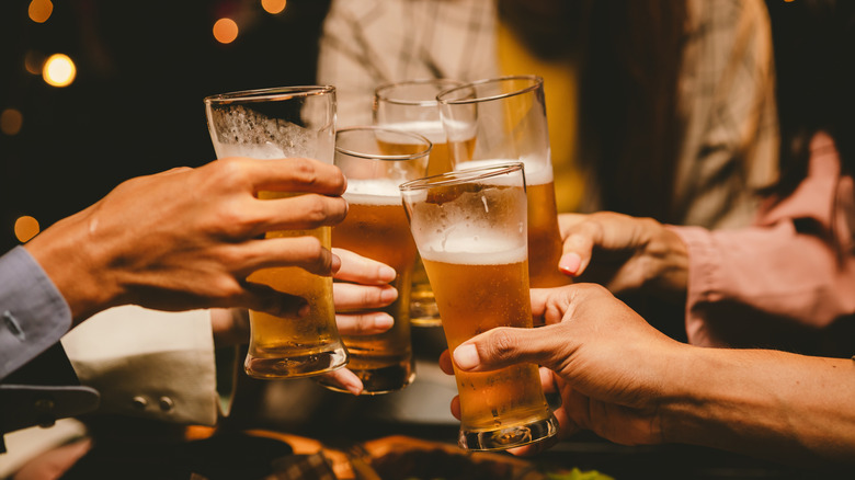 People clinking drinks at bar