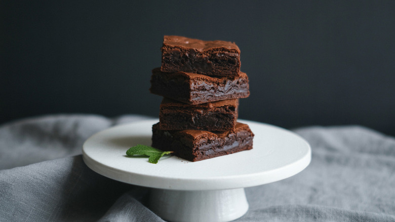 Stack of fudgy brownies on a white plate