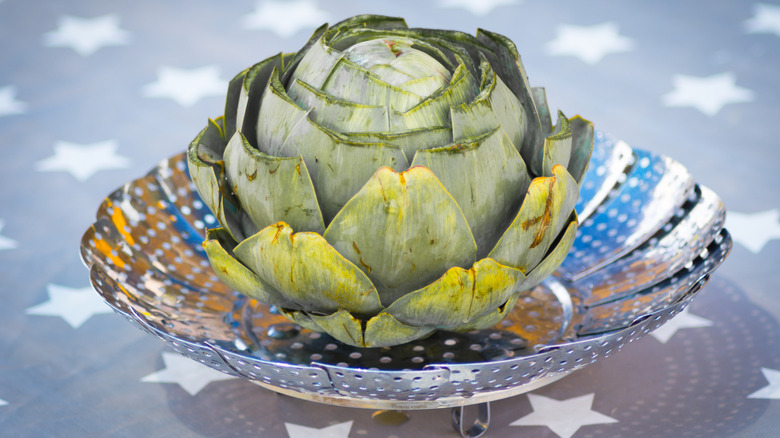 Whole artichoke in colander on star-patterned table
