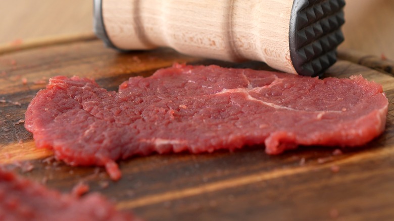 Steak and meat mallet on a cutting board