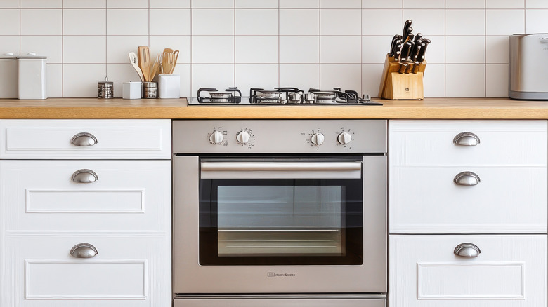 White kitchen with stainless steel appliances, white cabinets, and light wood floors in Montreal