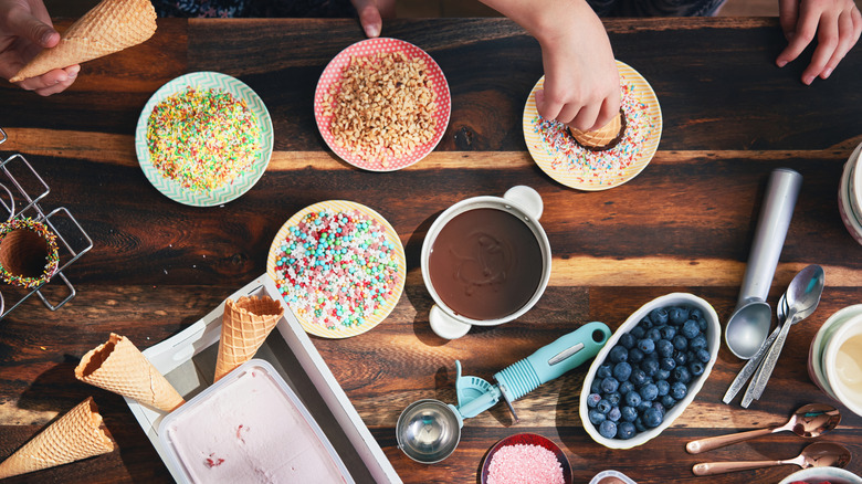 Overhead image of hands making ice cream cones with sundae ingredients
