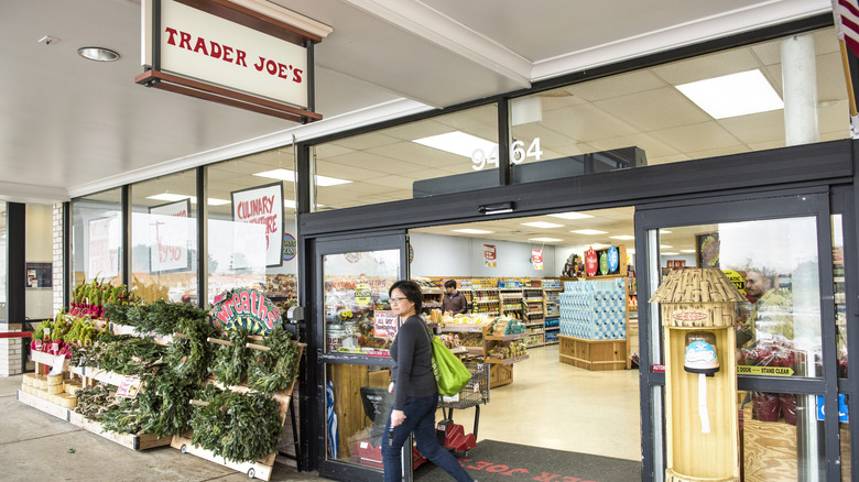 A woman walks out of Trader Joe's with a tote bag on her shoulder
